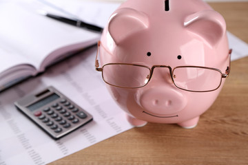 Pig moneybox and calculating equipment on desk closeup