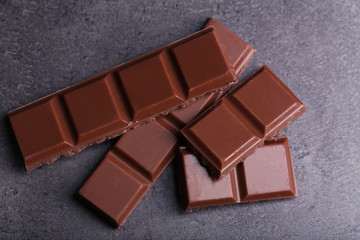 Milk chocolate pieces on gray background