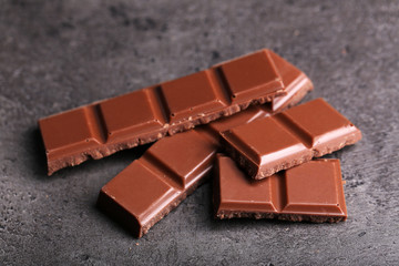 Milk chocolate pieces on gray background