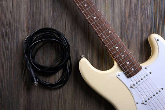 Guitar with cord on wooden background