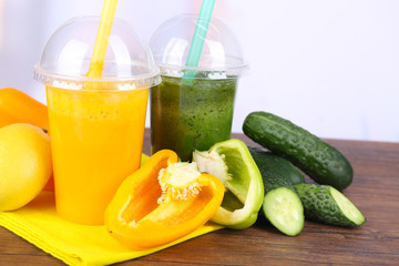 Fresh vegetable juices on color wooden table, on bright background