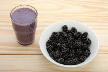 Smoothie from blackberries  in a glass and blackberries  on wood