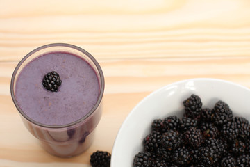 Smoothie from blackberries  in a glass and blackberries  on wood