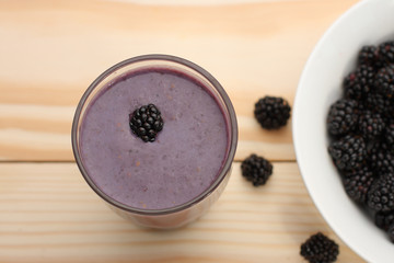 Smoothie from blackberries  in a glass and blackberries  on wood