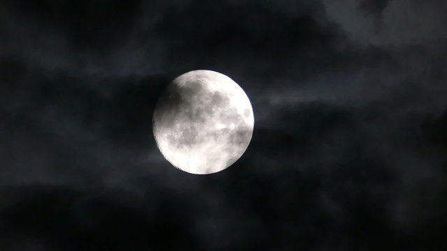 full moon moving between clouds
