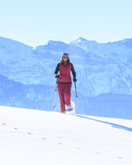 Fototapeta na wymiar gutgelaunte Frau wandert mit Schneeschuhen
