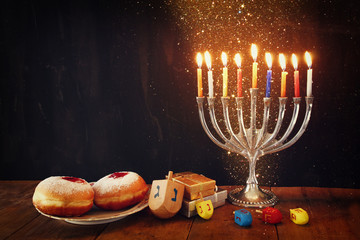 image of jewish holiday Hanukkah with menorah (traditional Candelabra), donuts and wooden dreidels (spinning top) © tomertu
