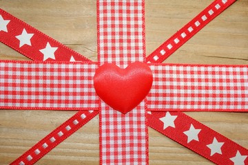 Red ribbon in a union jack design with a red love heart on a rustic wooden surface