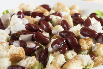 Delicious salad of beans, cabbage, onion, egg, cucumber, served in a white bowl.