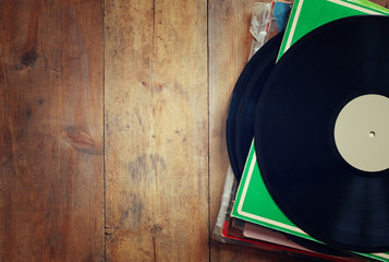 records stack with record on top over wooden table. vintage filtered
