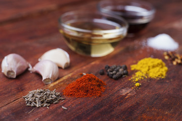 Assorted colorful powder spices on wooden brown rustic board with olive oil