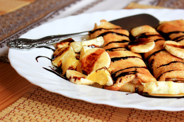 Pancakes stuffed with semolina, bananas and oranges drenched
