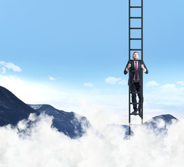 A businessman is climbing up the ladder. Clouds and mountain landscape. The concept of the success.