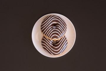 donut with chocolate-colored zebra on a black background. top view. space for inscriptions.