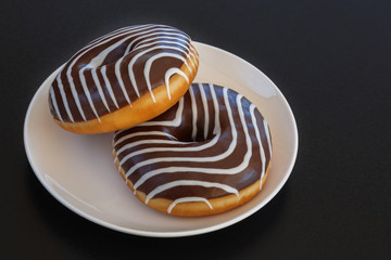 donut with chocolate-colored zebra on a black background. top view. space for inscriptions.
