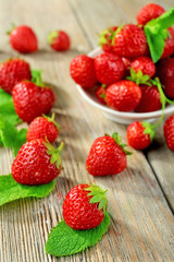 Ripe strawberries in saucer on wooden table, closeup
