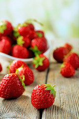 Ripe strawberries in saucer on wooden table on blurred background