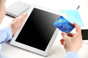 Man holding credit card and tablet on workplace background