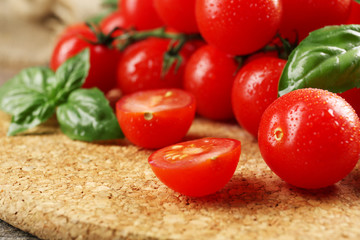 Cherry tomatoes with basil on wooden table close up