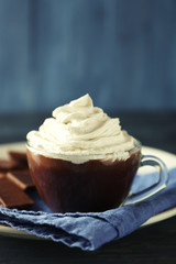 Cup of coffee with cream on color wooden background