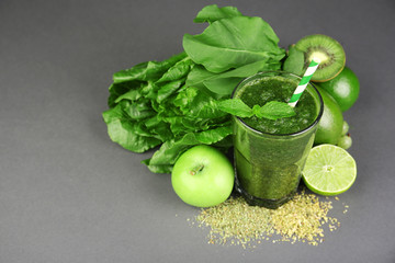 Green healthy juice with fruits and herbs on gray background