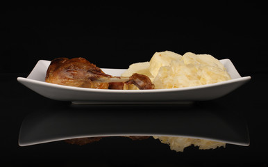 Roast duck, cabbage and dumplings on black background