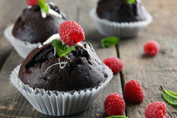 Delicious chocolate cupcakes with berries and fresh mint on wooden table close up