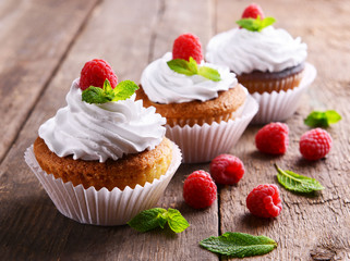 Delicious cupcakes with berries and fresh mint on wooden table close up