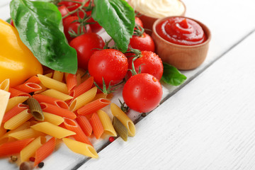 Pasta penne with tomatoes, cheese and basil on color wooden  background