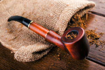 Smoking pipe and tobacco on brawn  wooden table.