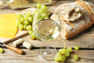 Still life of wine, grape, cheese and bread on rustic wooden background