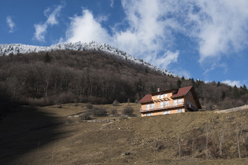Naklejka premium Forest covered with snow and a hotel in Bucegi Mountains, Prahova county, Romania.