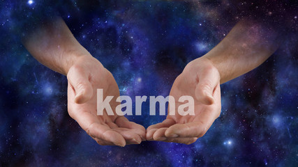 Fototapeta na wymiar Cosmic Karma is in Your Hands - Male hands emerging from a deep space night sky dark blue background, cupped cradling the word KARMA 
