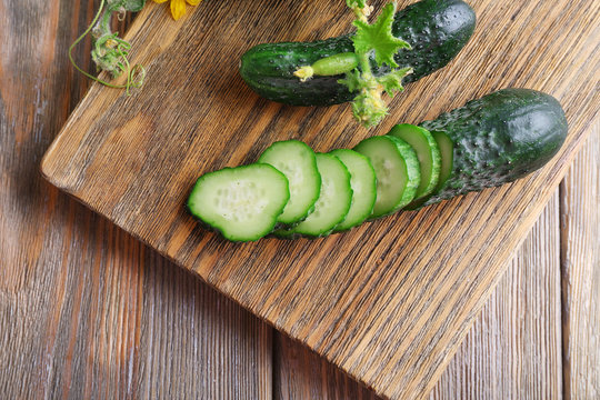 Sliced cucumbers and kitchen board on wooden background