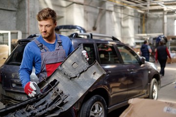 Fototapeta na wymiar Mechanic with car bumper in a workshop