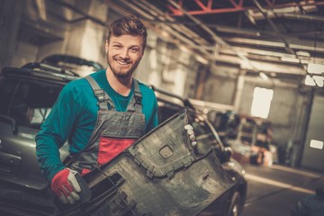 Obraz na płótnie Canvas Mechanic with car bumper in a workshop