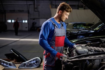 Fototapeta na wymiar Mechanic checking under hood in a workshop