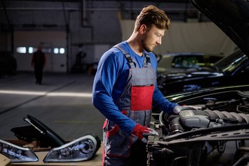 Mechanic checking under hood in a workshop