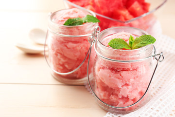 Watermelon ice cream in glass jars  on color wooden background