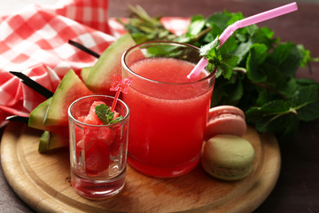 Cold watermelon desserts and drinks in glasses, on wooden table background
