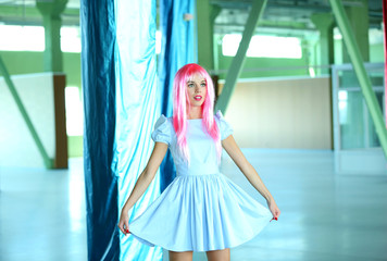 Young woman in mini dress posing like doll inside empty building