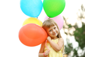 Fototapeta na wymiar Little girl with balloons outside