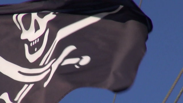 Black pirate flag waving on sunny windy day