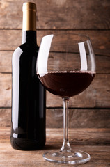 A bottle of red wine and a glass on wooden table