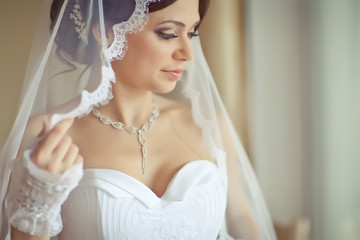 Beautiful young woman in white dress preparing herself to wedding  