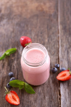 Healthy strawberry yogurt in cupping-glass with mint and berries on wooden background