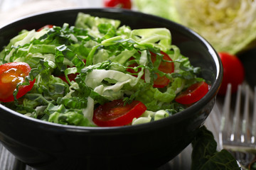 Savoy cabbage and tomato salad served in bowl on wooden table
