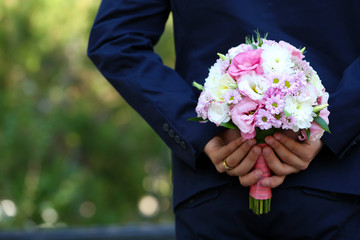 Groom holding bouquet behind his back