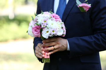 Groom holding wedding bouquet outdoors