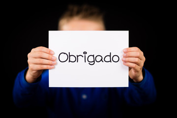 Child holding sign with Portuguese word Obrigado - Thank You